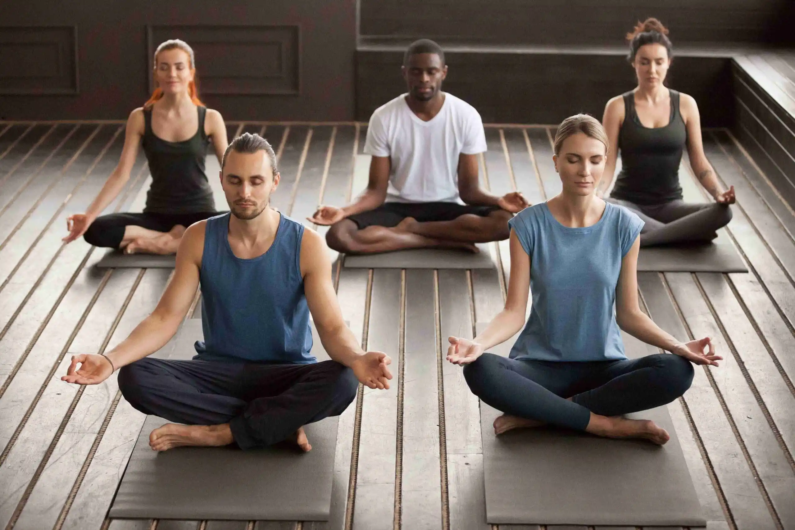 A diverse group peacefully meditates in a yoga class