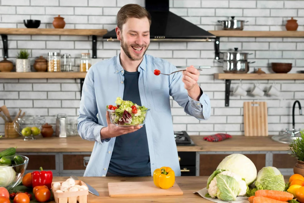 happy man standing kitchen eating fresh salad with fork